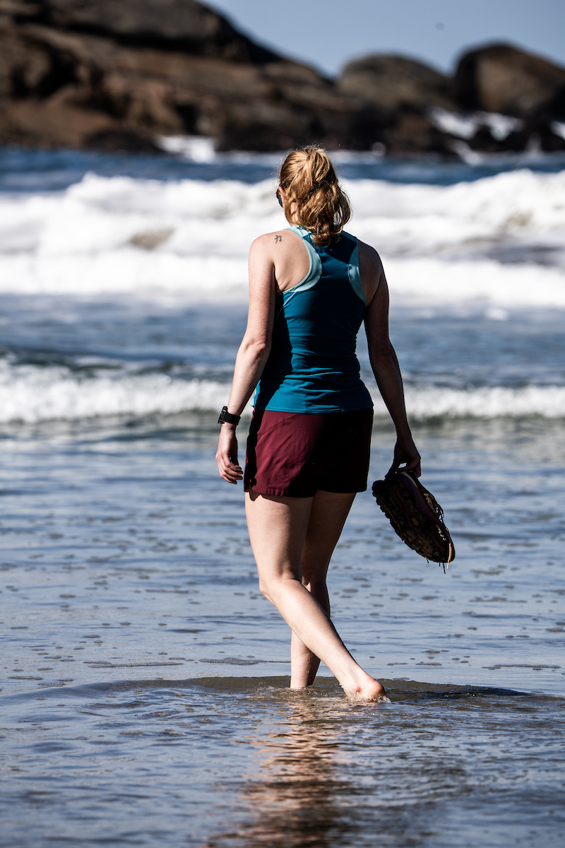 Dame på stranden med beina i vannet