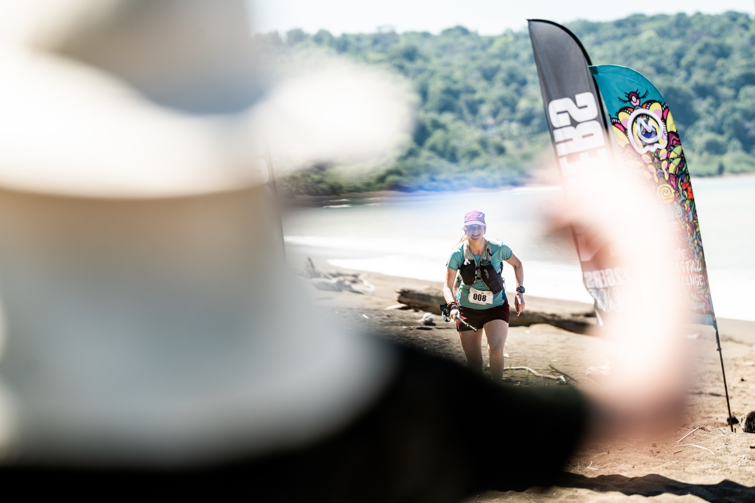 Løper i bakgrunnen som løper mot målgang. Person står klar med medalje i forgrunnen